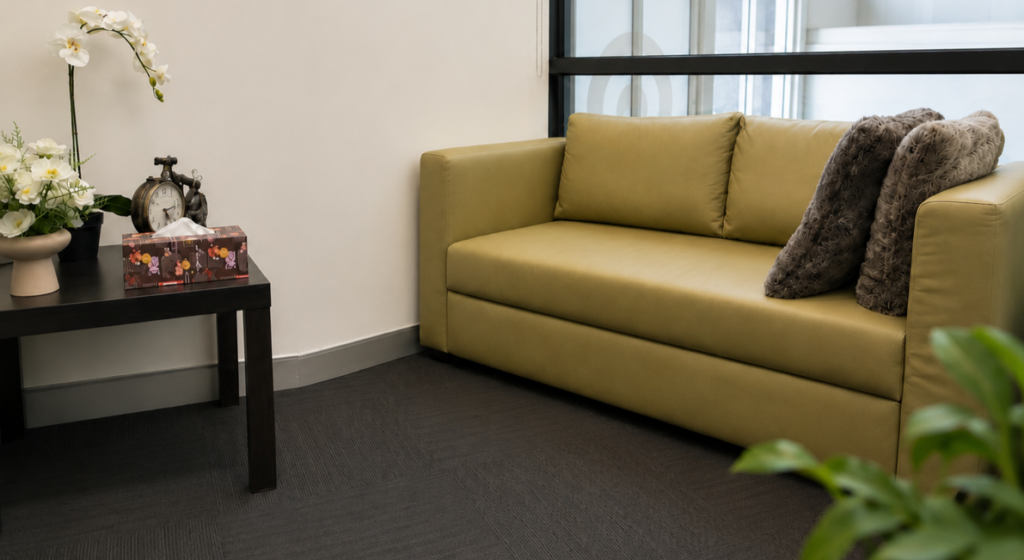 Therapy room at SzuYing Psychology featuring a comfortable green sofa and calming consultation space.